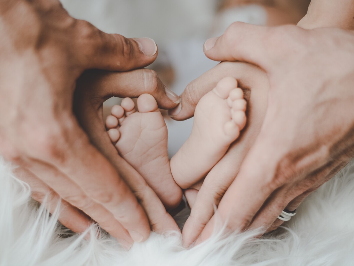 小さい赤ちゃんの足に手を添える両親